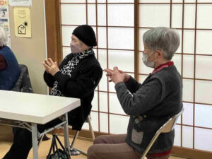 参加者が椅子に座ったまま、手の動きを使った運動に取り組んでいる様子。