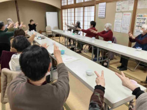 参加者が両腕を前に伸ばし、コグニサイズの動きをそろえて行っている場面。