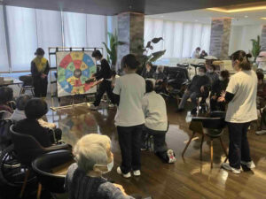 高校生と大学生がデイケア利用者と交流しながら介護体験を行う様子