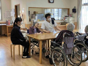 鹿児島商業高校の生徒が特別養護老人ホームたにやまの里でスタッフと一緒に利用者様との交流を体験する様子