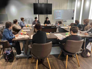 坂之上地域のかごサポで行われた福祉相談会で、スタッフがホワイトボードを使いながら介護施設の種類や料金について説明している様子