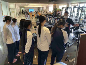 デイケアリハビリセンター前之浜で高校生がリハビリ機器の説明を受けている様子（体験学習）