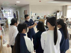 介護老人保健施設サンシャインきいれで高校生がスタッフから介護業務の説明を受けている様子