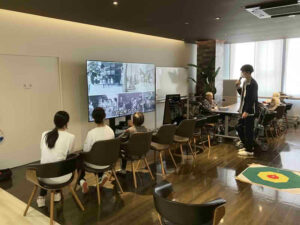 デイケアリハビリセンター前之浜で映像を見ながら説明を受ける高校生の様子