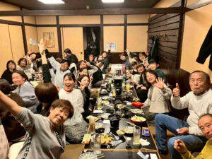 多くのスタッフが笑顔で手を振る活気ある親睦会の様子