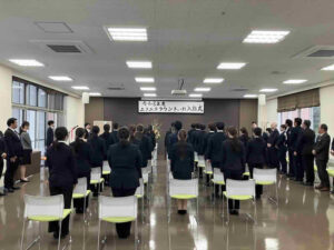 入社式で起立する新入職員の様子　緊張感のある式典の一場面