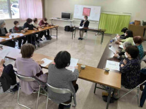 在宅介護の事例説明を聞きながら資料に目を通す参加者の様子と講話の風景