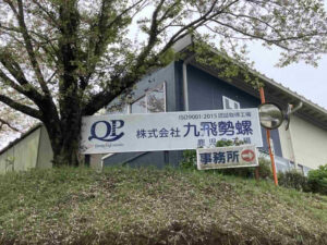 株式会社九飛勢螺の工場看板と施設外観の様子