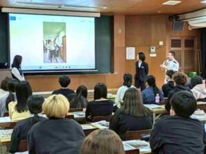 複数の卒業生スタッフが前に立ち、学生に向けて介護福祉士課程の体験や進路について説明している教室風景