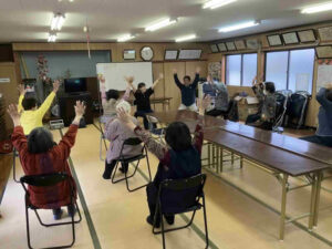 森山公民館で開催された福笑会サロンにて、参加者が椅子に座りながら手を上げるコグニサイズに取り組んでいる様子