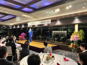 きいれセントラルクリニック10周年記念祝賀会で、会場のステージ上から挨拶を行っている様子