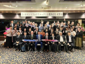 きいれセントラルクリニック10周年記念祝賀会で、参加者の皆さまが会場ステージ前に集まり集合写真を撮影した様子
