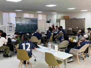第3回ゆな愛ご褒美マルシェで、鹿児島ユナイテッドFCを応援する来場者が大型モニターを観覧する様子