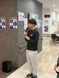 第3回ゆな愛ご褒美マルシェで、川島巧奨選手がマイクを持って来場者へ挨拶する様子