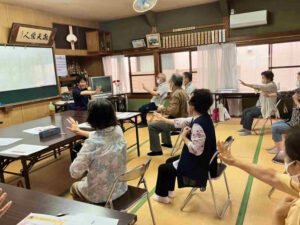 一番組お達者クラブの参加者が、たにやまの里施設長の説明に合わせてコグニサイズを実践している様子