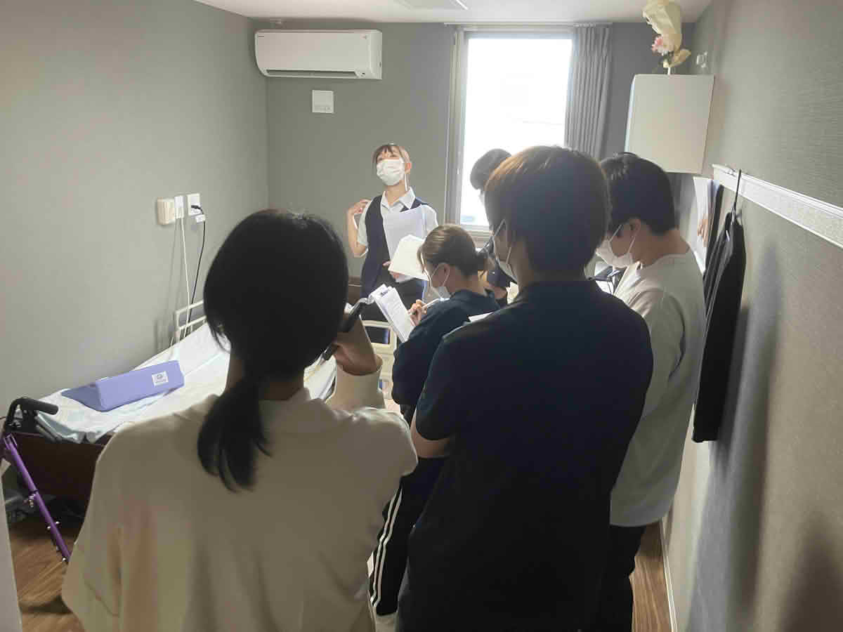 うすきの里の居室で、学生がベッド周辺の福祉用具や介護テクノロジーについて学んでいる様子