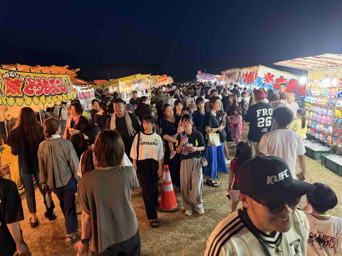 明るく照らされた屋台が並ぶ会場を、多くの来場者が行き交う第39回喜入夏まつりの様子