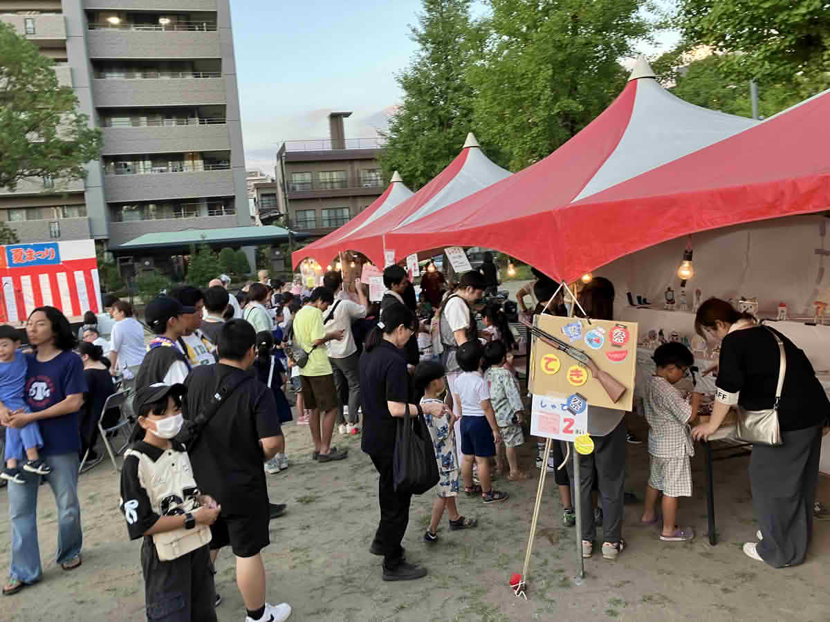 第43回小松原一丁目町内会夏祭りで、赤と白のテントが並ぶ出店を楽しむ来場者の様子