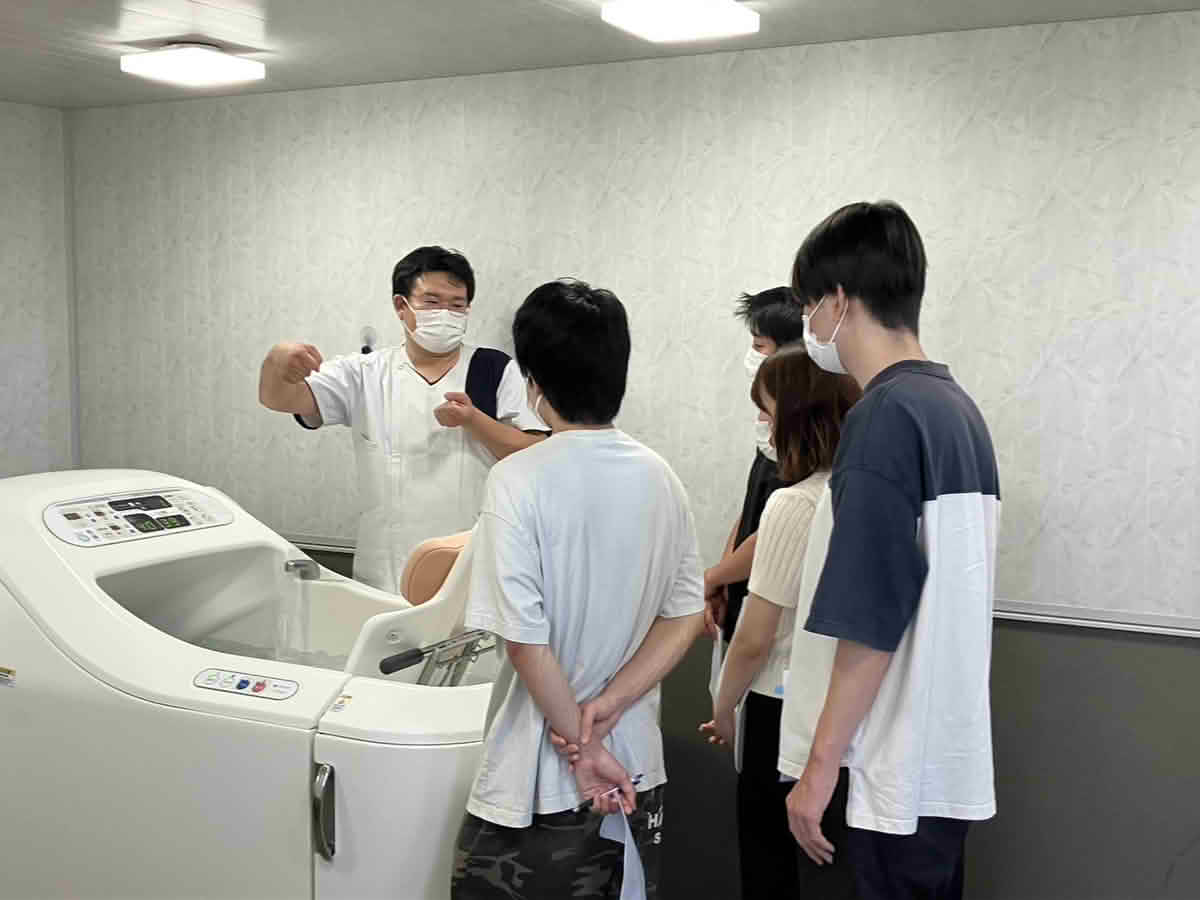 特殊浴槽の機能や使用方法について、職員から説明を受ける鹿児島国際大学 中井ゼミの学生