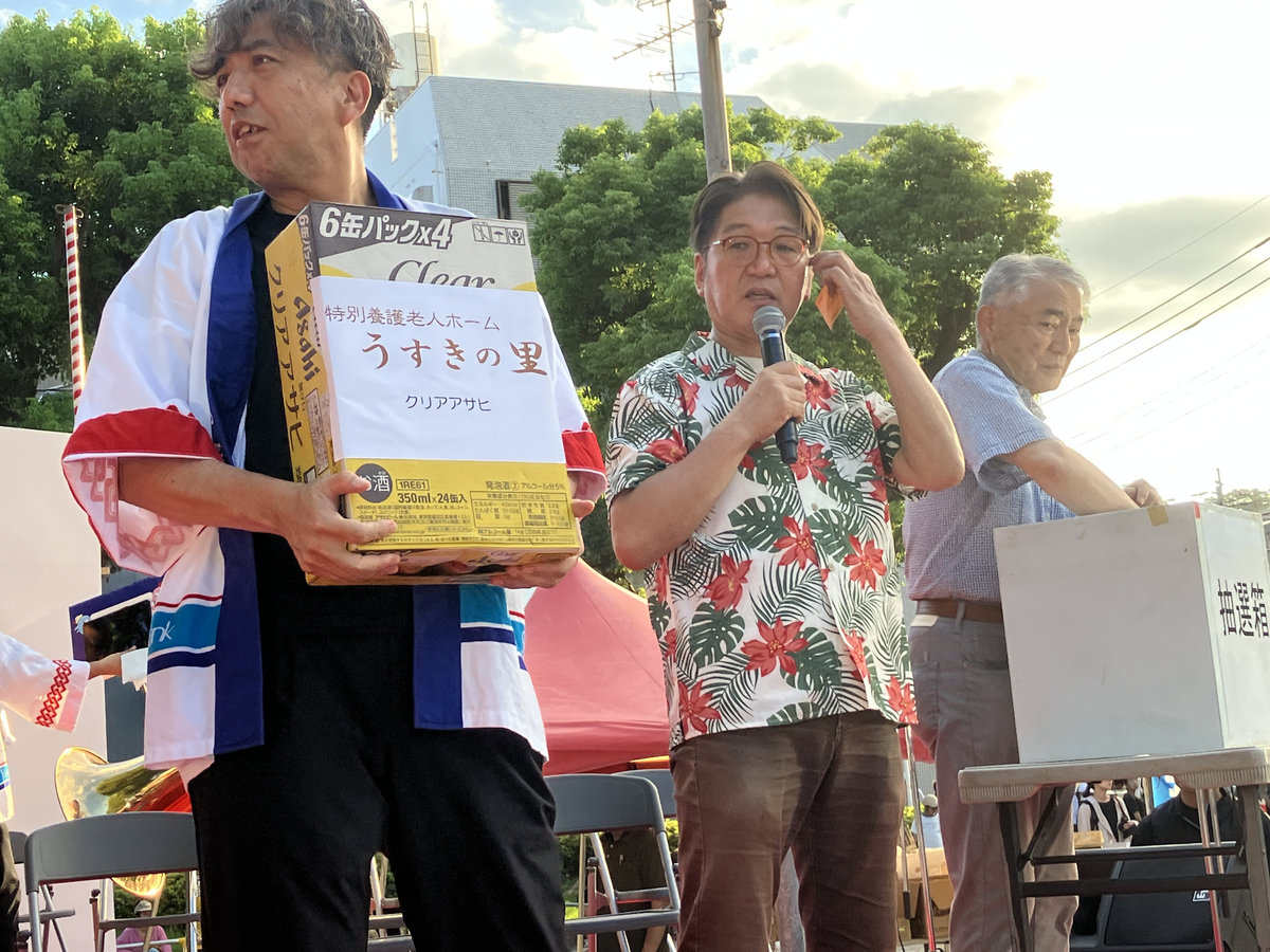 第43回宇宿納涼夏祭りのステージで、うすきの里が実行委員会へ寄付した品物を紹介する様子