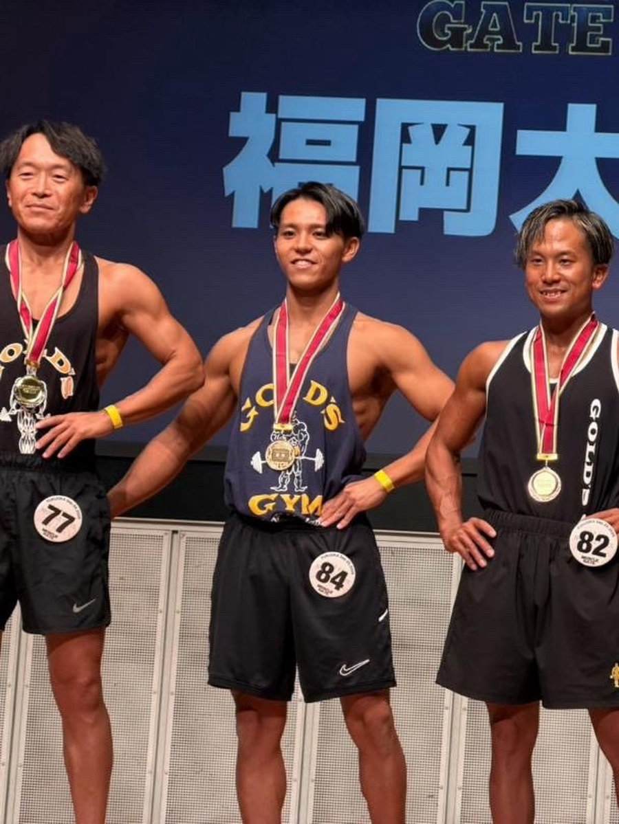 マッスルゲート2026福岡大会の表彰後、メダルをかけて並ぶ選手たち。中央はメンズタンクトップ一般の部で優勝した当グループの理学療法士。