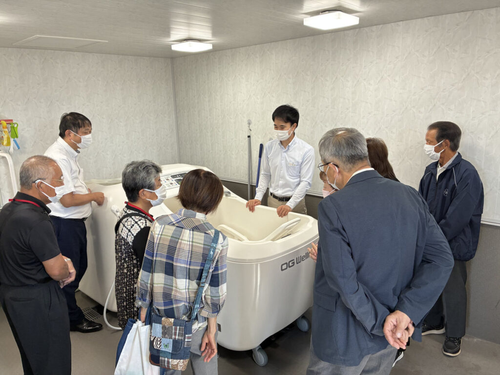 うすきの里の設備を囲み、職員から説明を受ける喜入民児協の参加者。