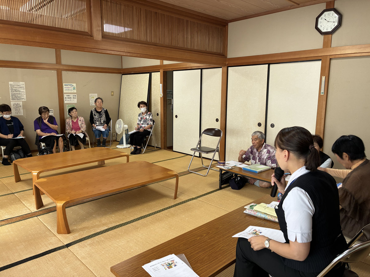 福平福祉館で、マイクを持った講師が向原お達者クラブの参加者に認知症について説明する様子