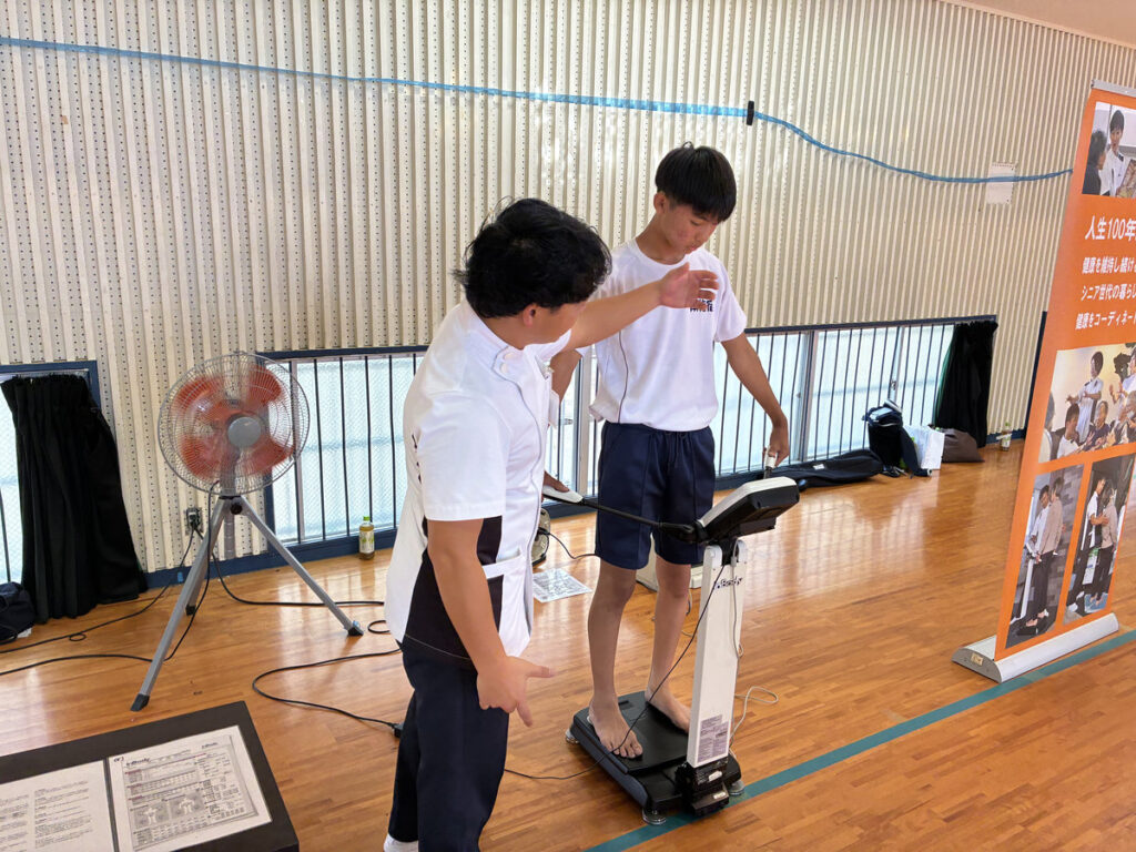 南指宿中学校の福祉体験学習で、生徒がスタッフの付き添いのもと、身体に不自由がある状態を疑似体験している様子